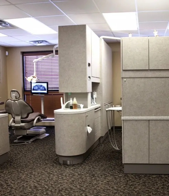 Open treatment bays, with a patient chair and an overhead monitor showing an x-ray.